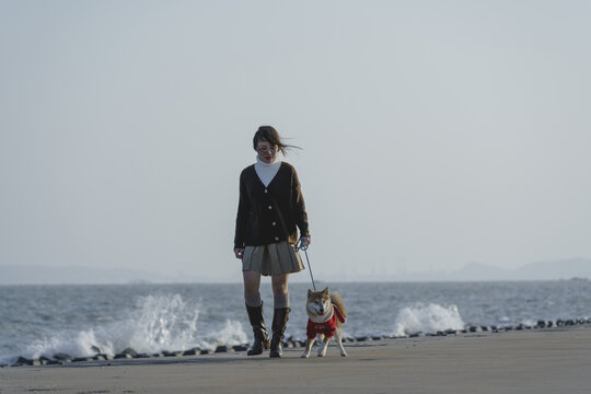 女孩在海边牵着柴犬看海
