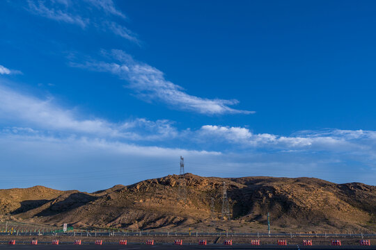 蓝天白云下新疆戈壁山丘电塔