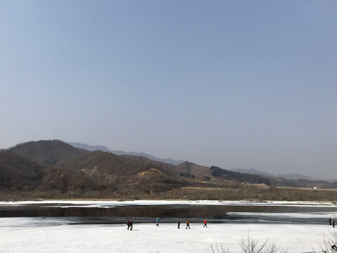 行走在半冻半化河上的人们