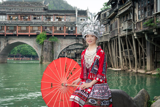 沱江边撑着红伞的苗族姑娘