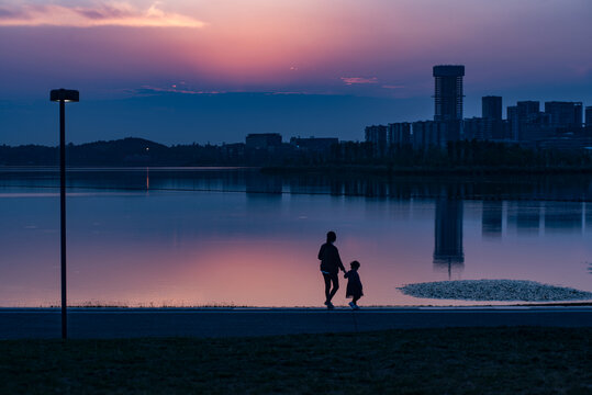 夕阳下公园湖边母女散步