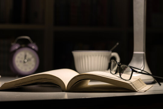 晚上桌面上打开的书和眼镜