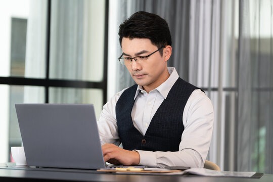 一个商务男士坐在办公桌前使用电脑