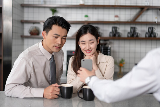 伙伴在茶水间一起开心看手机