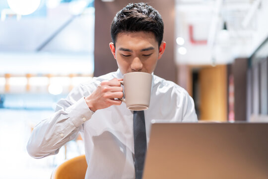 白领使用笔记本电脑认真专注地工作喝咖啡