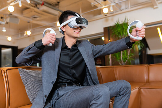商务人士坐在沙发上玩VR游戏机