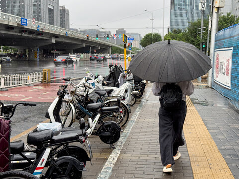 北京暴雨中打伞的路人