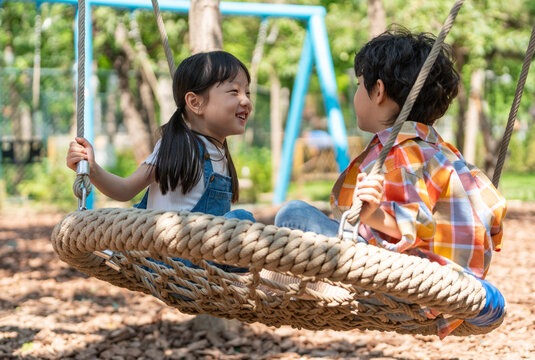 两个小孩子面对面开心荡秋千