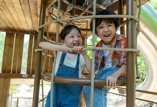 两个小孩子开心爬绳网攀爬架