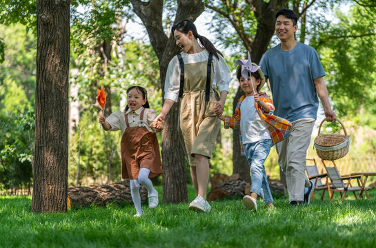 一家四口露营在草地上开心奔跑