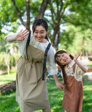 妈妈拉着女儿的手开心招手