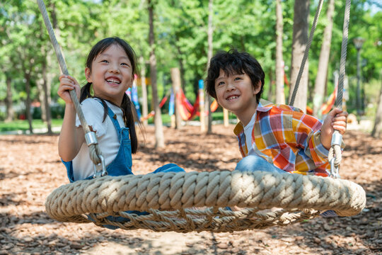 两个小孩子面对面开心荡秋千