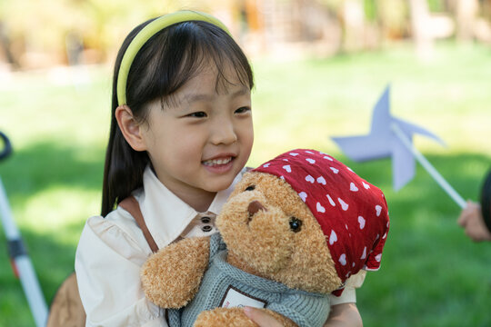 女孩抱着玩具熊坐在露营车上微笑