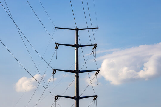 蓝天白云背景前的供电输电塔