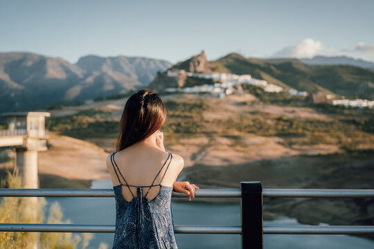 一名女性在湖边欣赏远处的山城