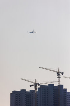 天空低空飞行的飞机与建筑工地