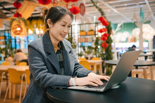 亚洲女性在笔记本电脑前侧面视角