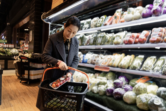亚洲女性在超市选购有机蔬菜场景