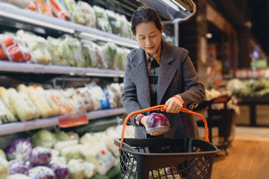 亚洲女性在超市选购新鲜蔬菜特写