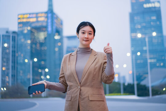 城市夜晚自信女性手持手机举拇指