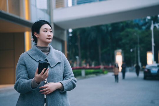 自信女性拿着手机行走在街道上