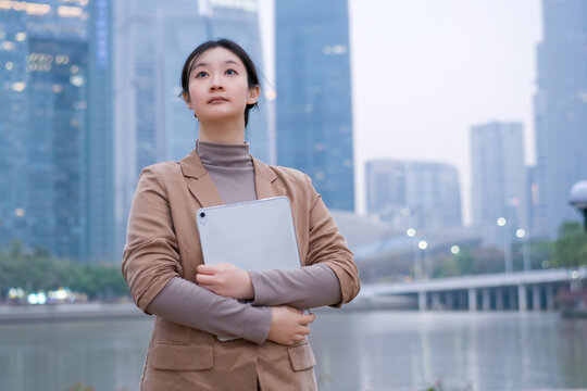 自信女性抱着电脑在夜晚江边