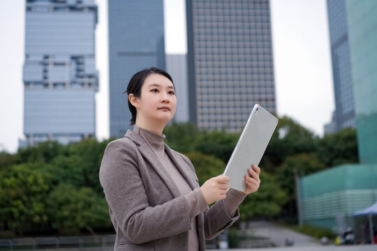 摩天大楼外自信女性使用平板电脑