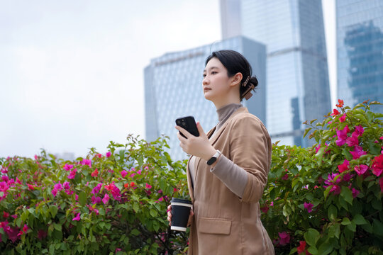 自信女性手持手机咖啡行走在街头