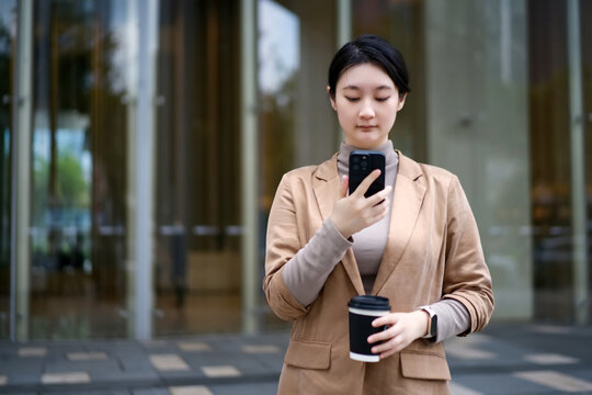 走出办公室茶歇时看手机的女性