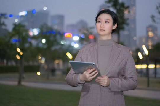 拿着平板行走在城市夜晚的女性