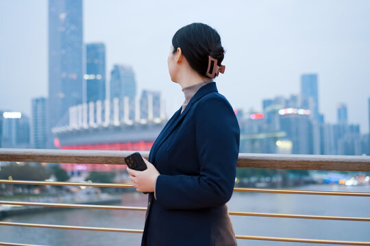 在城市桥上职业女性凝视摩天大楼