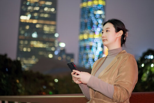 职业女性手持手机走在城市夜晚