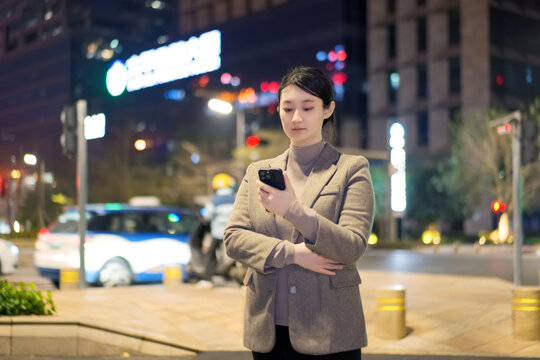 在傍晚街道上查看手机的职业女性