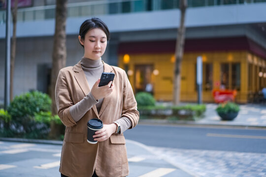 在办公楼外茶歇看手机的赋权女性