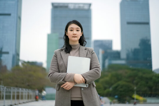 在城市街道上手拿电脑的自信女性