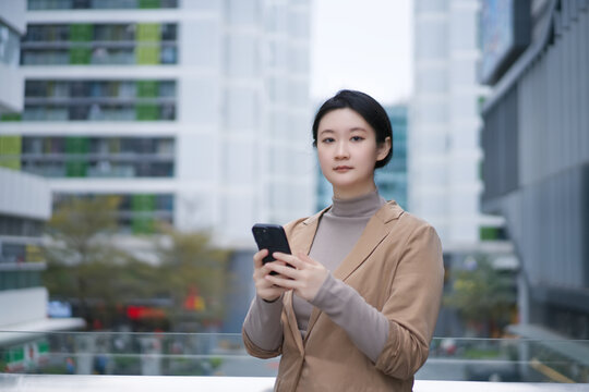 职业女性手拿手机行走在户外