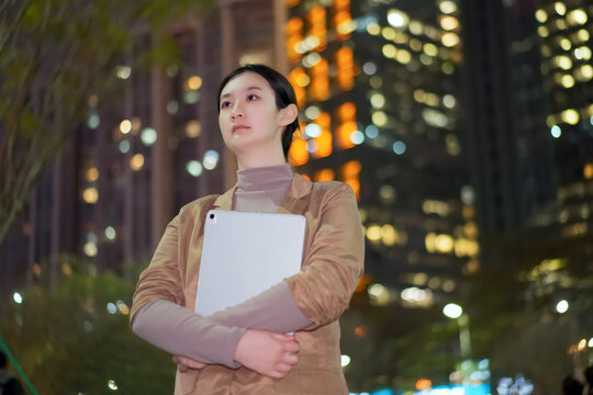 在城市夜晚里职业女性手持电脑