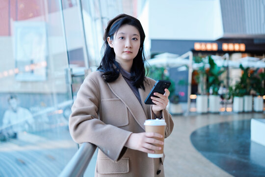 年轻女性在商场手持智能手机