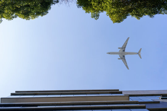 飞机在蓝天下飞越高楼建筑