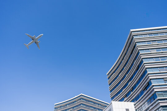 飞机在蓝天下飞越高楼建筑