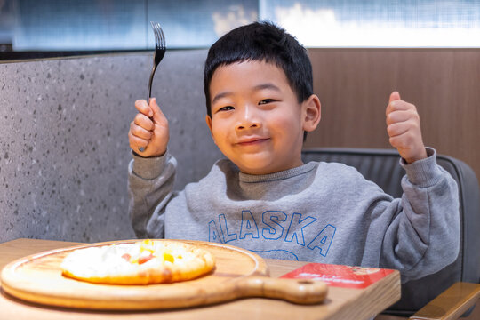 一个小男孩开心吃披萨