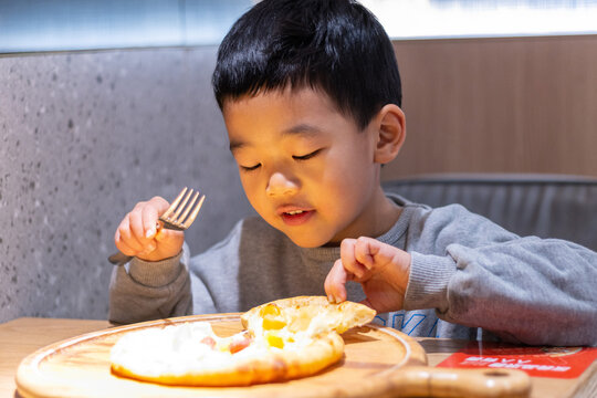一个小男孩开心吃披萨
