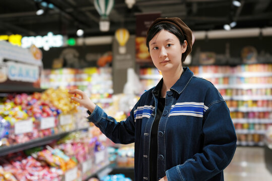 年轻女性在超市货架挑选商品