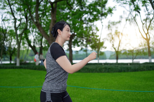 身穿运动服的年轻女性在公园奔跑