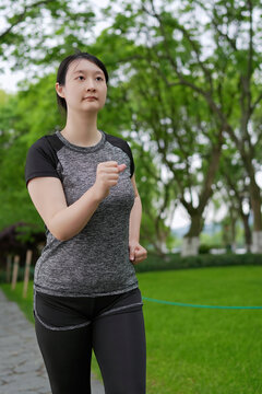 户外年轻女性在绿色公园慢跑
