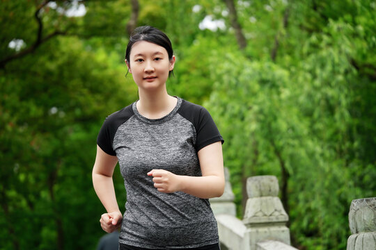 年轻女性在户外绿色公园慢跑健身