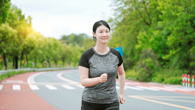 公园慢跑的年轻女性在自然景观中