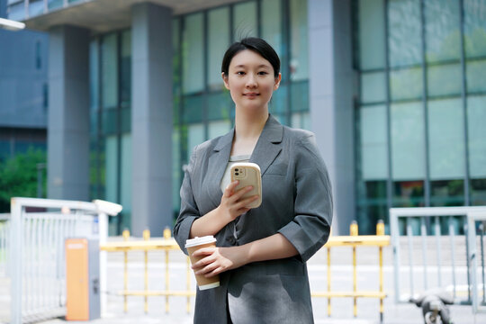 职业女性带着咖啡和智能手机出门