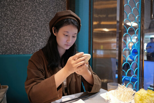 年轻女子在餐厅用智能手机雕刻