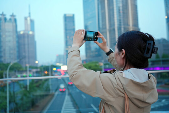 黄昏时游客用手机捕捉城市景观
